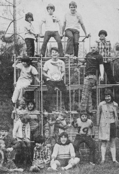 A newspaper picture of a group of youth posing on a metal climbing structure in the 1950's.