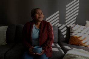 A woman sitting on a couch with a cup of coffee.