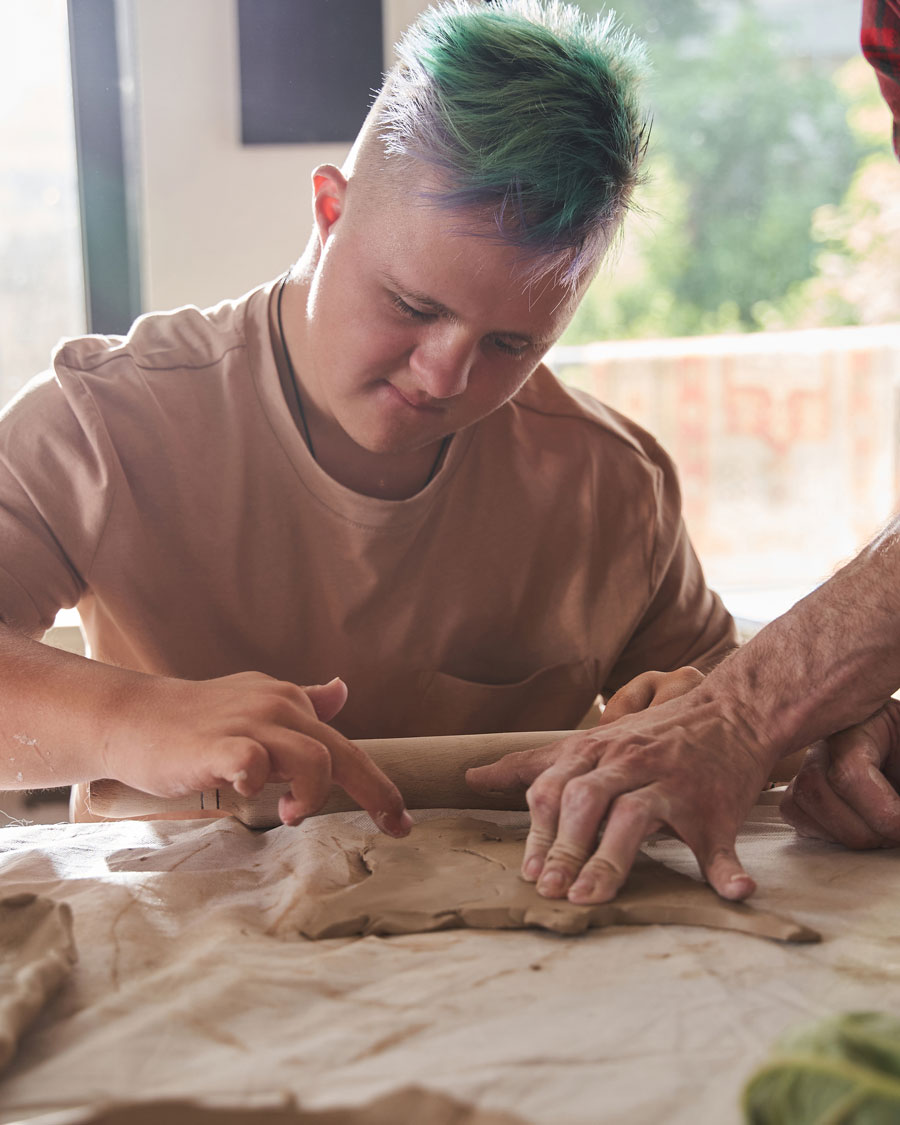 Teen boy with green spiked hair rolling out gingerbread dough