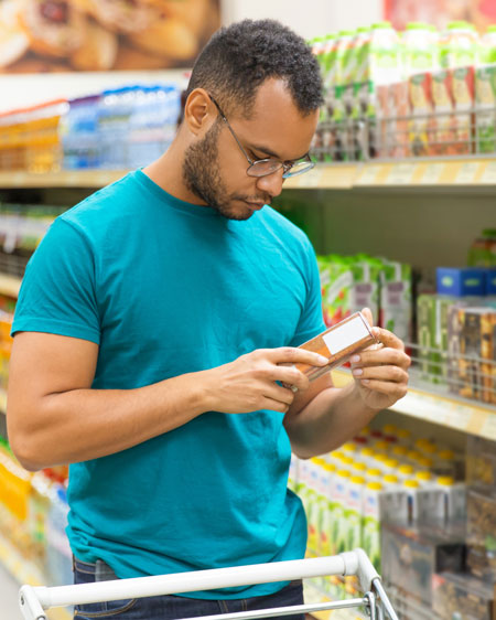 Un homme, en chemise bleue dans un magasin, lisant l’étiquette d'un article.