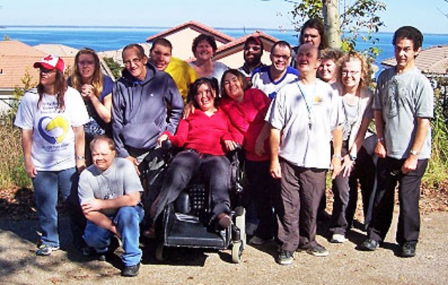 A group of supported people and helpers posing at the beach
