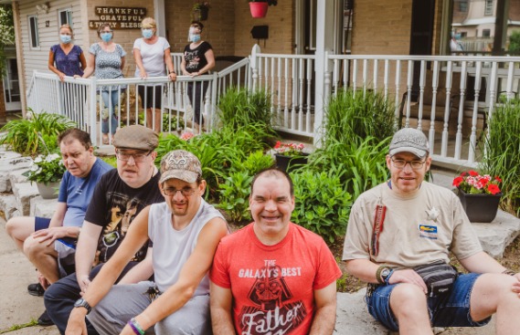 A group of supported adults sitting outside of a home